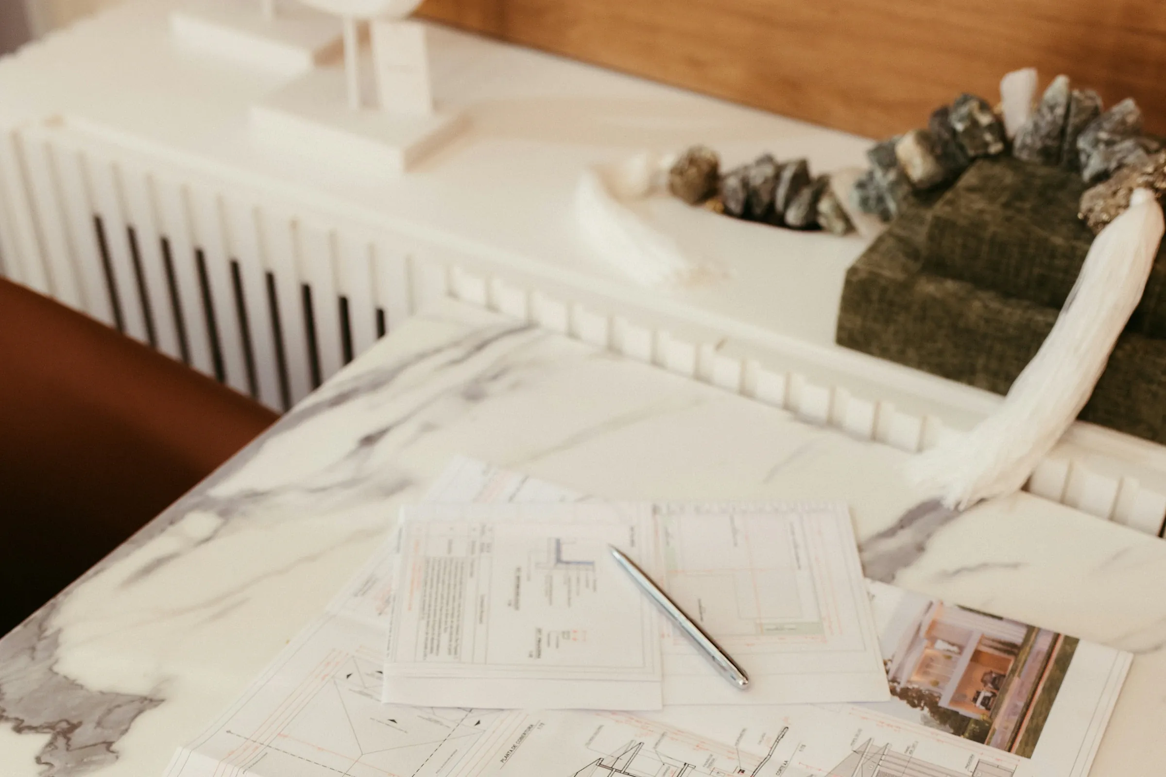 Documentary photograph of architectural drawings and a physical building model on a studio table